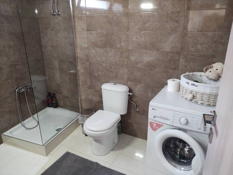 Nice apartment interior in Sitia, bathroom with toilet, shower, and washing machine.