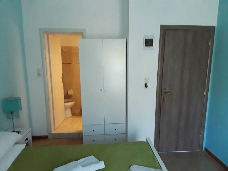 Interior of hotel room in Alinda: bed, cabinet, toilet, shower.