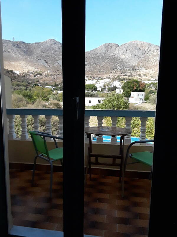 View from balcony of hotel room in Alinda: table, chairs, mountains with FM and TV broadcast transmitters on a peak.