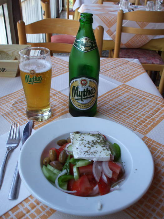 Greek village salad or horiatiki salata and a glass of Mythos Greek beer in a taverna in Delphi.