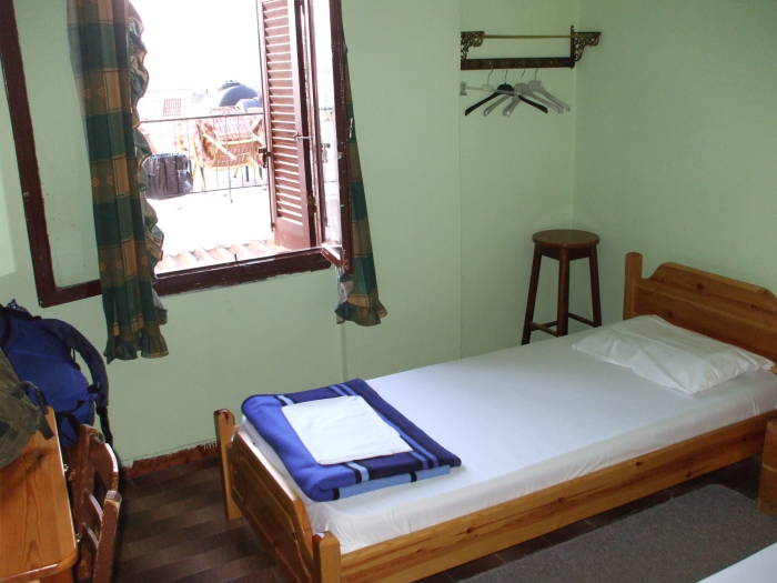 Interior of room at Dimitris Bekas guesthouse or domatia in Nafplio.  Two twin beds, wooden stool, desk and chair.