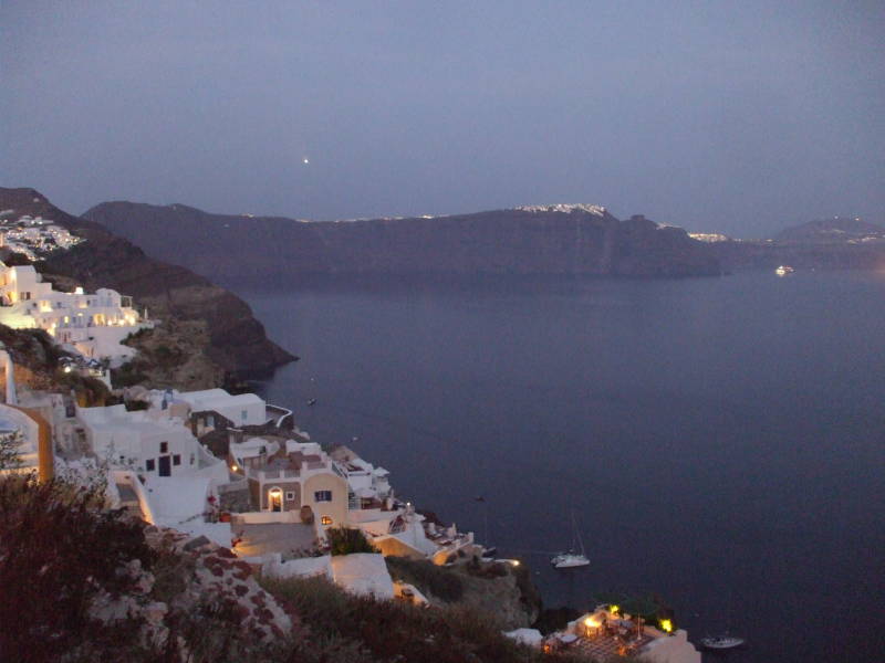 Lights come on as evening falls in Oia, a small town on the Greek island of Santorini.