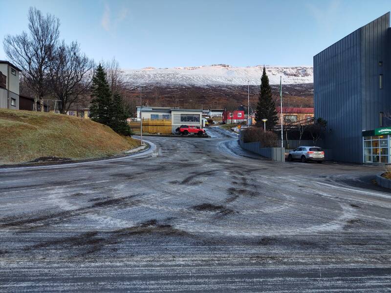 Icy streets and parking lot at the grocery store, liquor store, and post office in Fáskrúðsfjörður town.