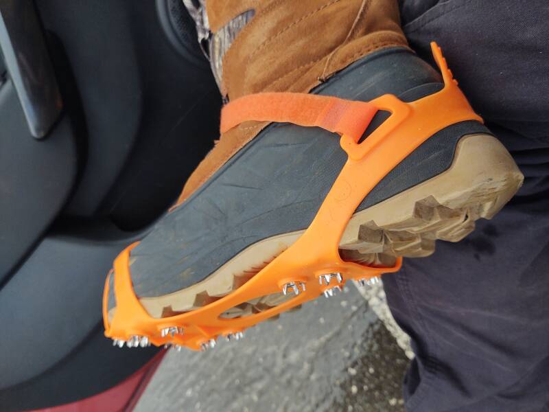 Wearing crampons over boots for walking on ice.
