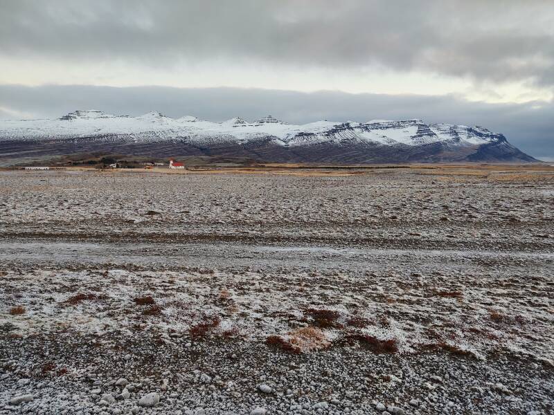 Slippery road near Breiðdalsvík, Lutheran church and mountains in the distance.