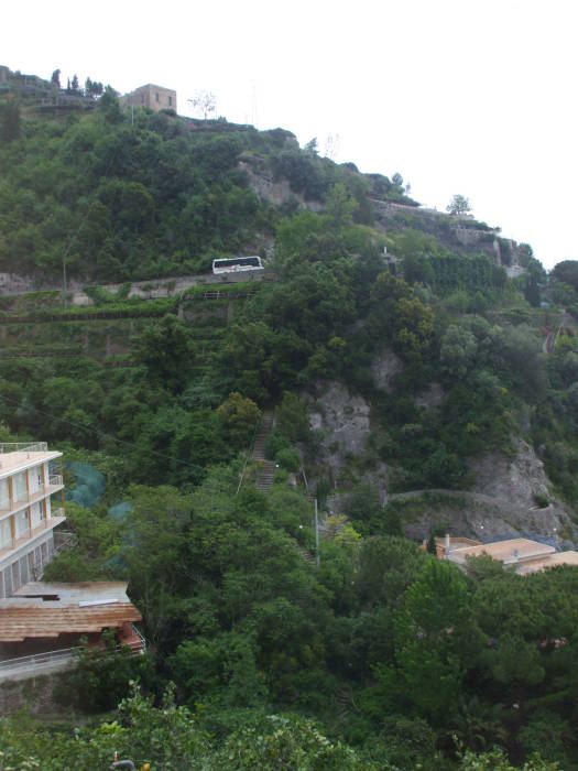 A crowded bus slowly ascends a steep grade on the narrow twisting road along the Amalfitani Coast.