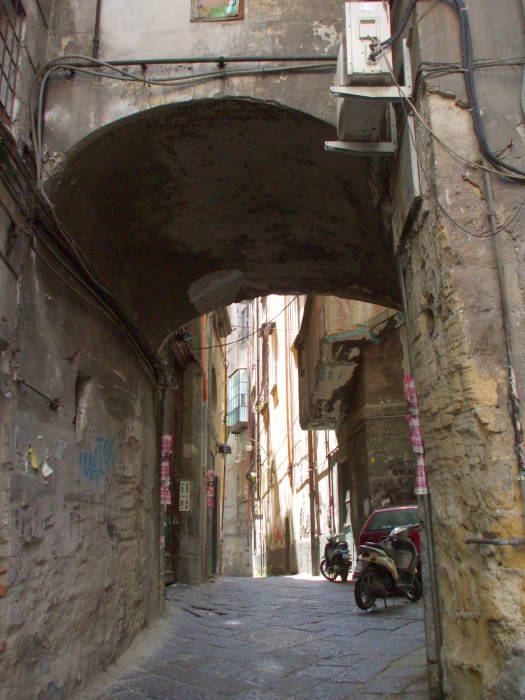An arched building spanning a narrow street in Naple's Centro Storico.