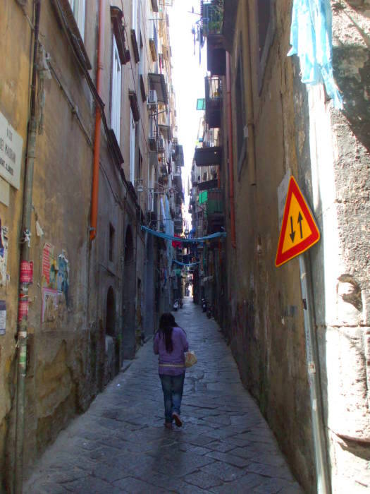 A narrow alleyway with laundry hanging overhead in Naples.