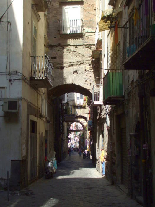 Large stone arches over a narrow street in the Centro Storico in Naples.