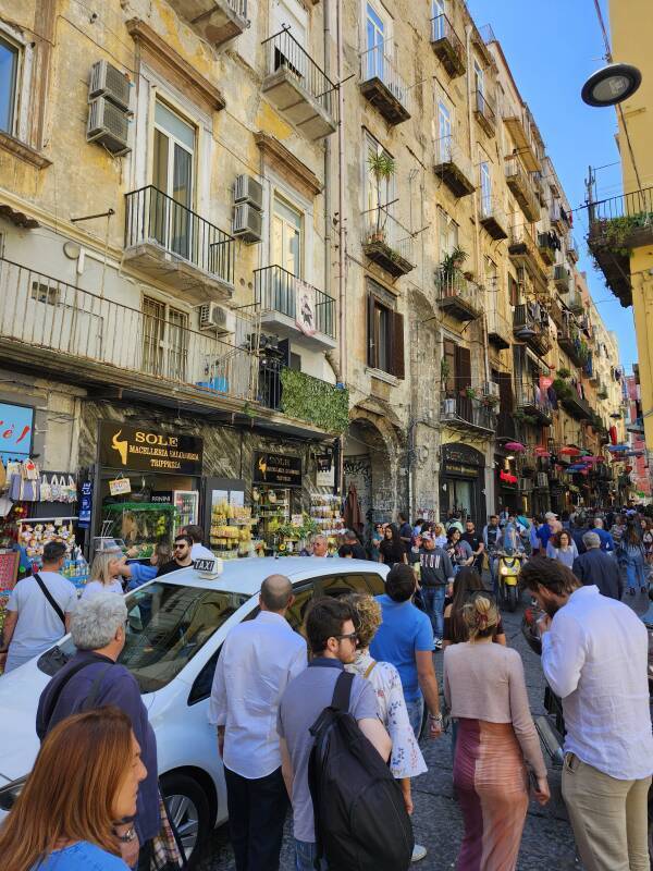 Crowds walking along Via dei Tribunali.