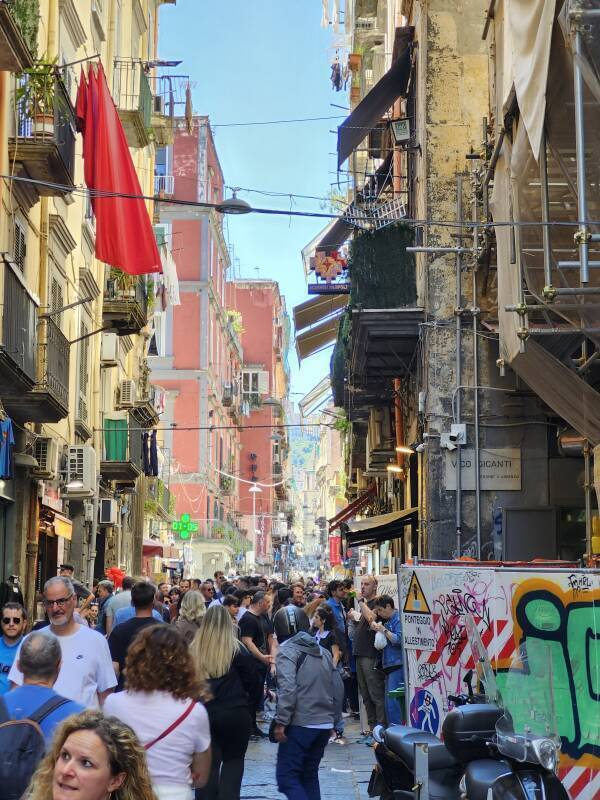 Crowds walking along Via dei Tribunali.