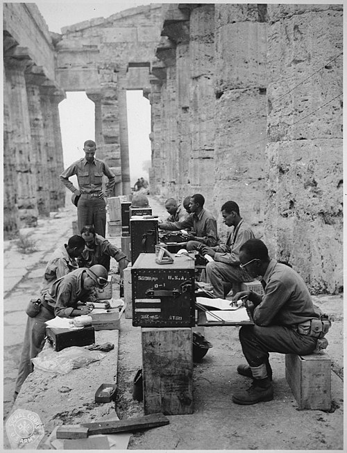 A company of men has set up its office between the columns (Doric) of an ancient Greek temple of Neptune, built about 700 B.C.