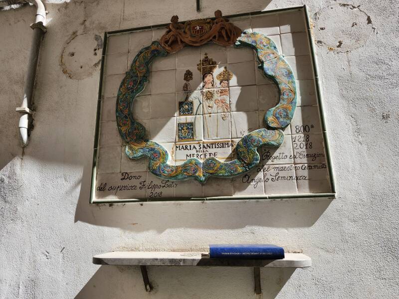 Book of Mormon placed on a street corner ceramic shrine to Holy Mary of the Mercy.