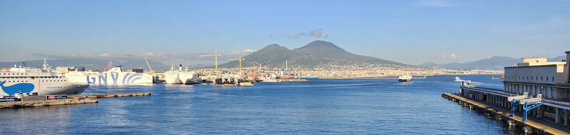 Napoli harbor in the sunset, passenger ferries in the foreground, Mount Vesuvius beyond.