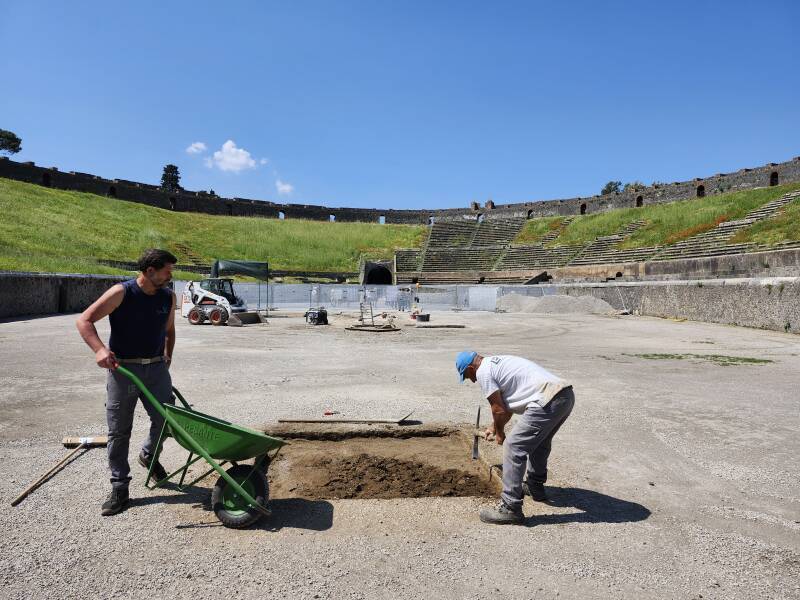 Men working on the floor of the amphitheatre at Pompeii.