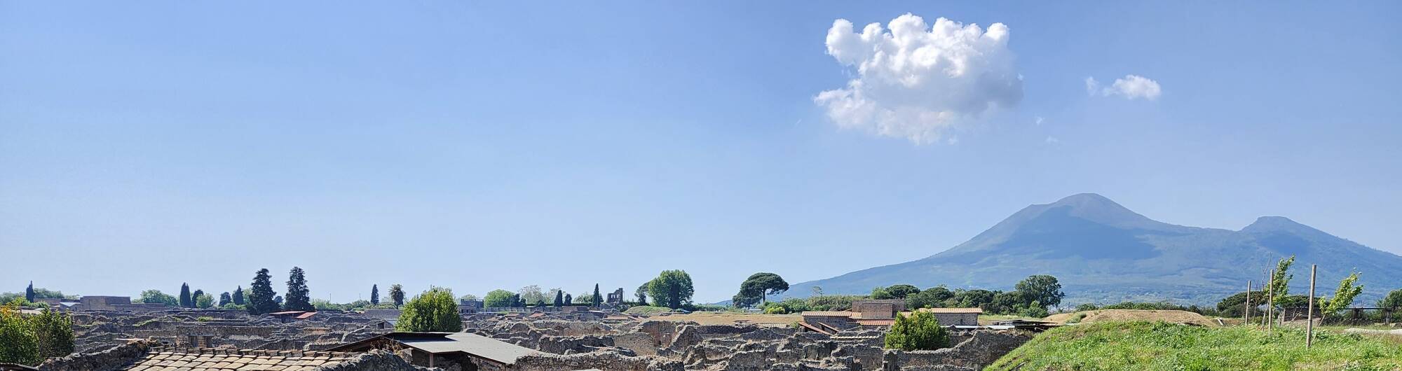 Excavated and still-buried sections of Pompeii, with Vesuvius looming ominously in the background.