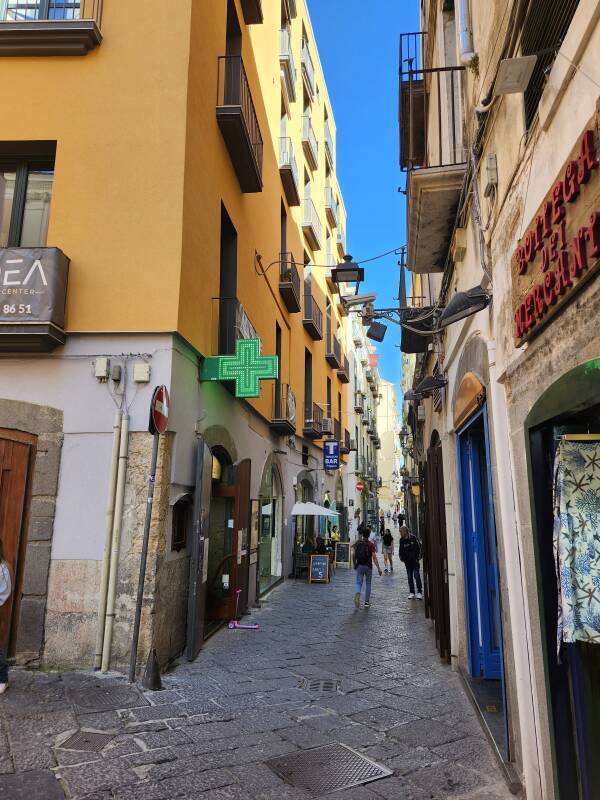 Narrow street, a pharmacy and a tabacchi on the left.