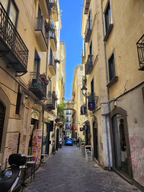 Narrow street, small tables outside cafes.