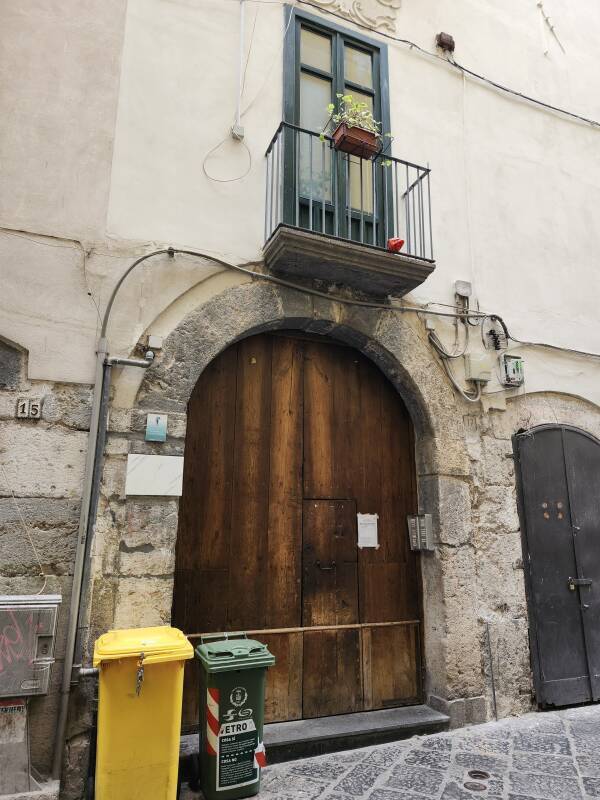 Large heavy wooden door with a smaller door within it, a panel of buzzers to the side.