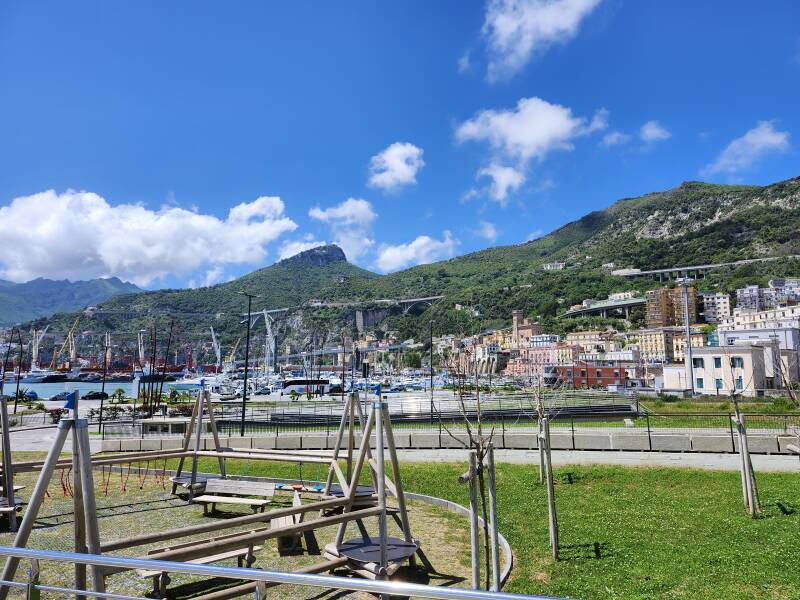 Park with mountains in the distance, arched highway bridges running through the mountains.