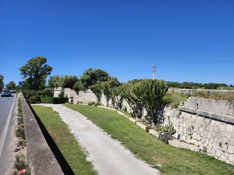 Old stone approach to the bridge with a gravel lane leading down from the highway.