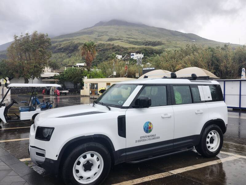 Vehicle belonging to Instituto Nazionale de Geofisica e Vulcanologia near the ferry pier on Stromboli, with the volcano's peak in the background.