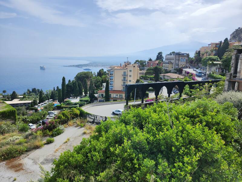 Road ascending from the coast road and Mount Etna as seen from the Belvedere di Via Pirandello viewpoint in Taormina.