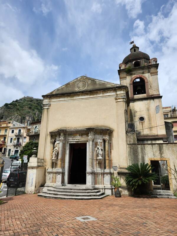 Façade of the Church of Saint Pancras, mountaintop fortress in the background.