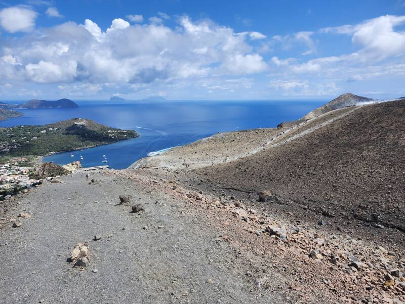 Crater rim path with people and steam vents in the distance.