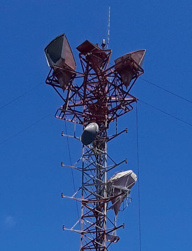 Cropped view of antennas at the top of a telecommunications tower with old horn antennas disconnected but still in place, along US 231 in Indiana.