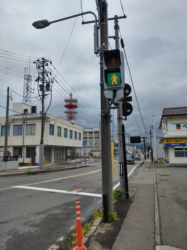 Blue pedestrian signal light and telecommunications tower in Kitakata.