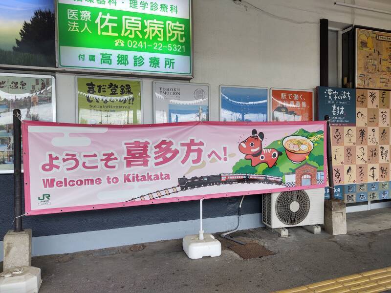 'Welcome to Kitakata' sign at Kitakata Station, with Akabeko and a bowl of ramen.