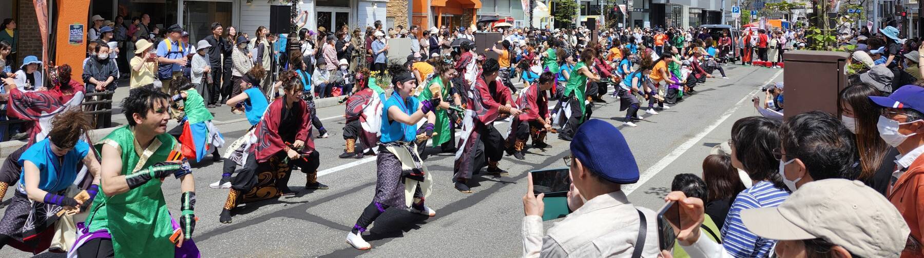 Dancers in colorful costumes and large banners at the Spring Festival in Aomori.