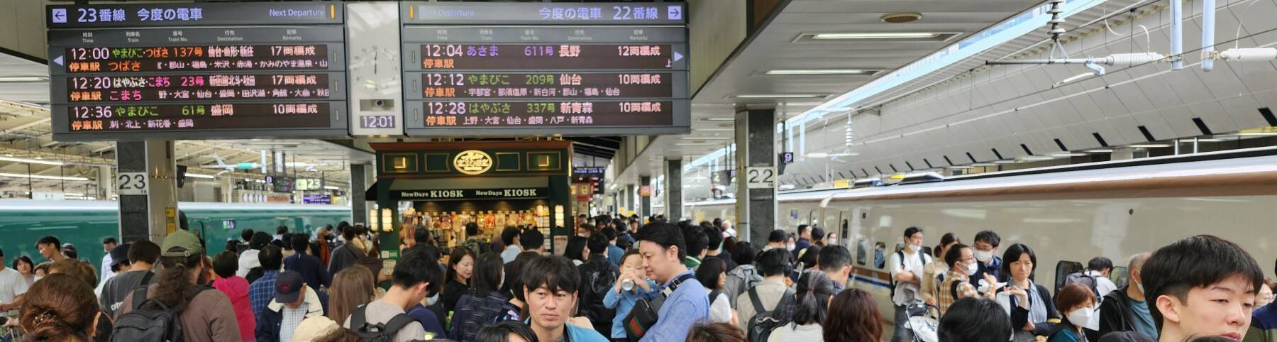 Schedule board shows my train above the crowd on a Shinkansen platform at Tōkyō Station.