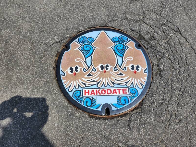 Multi-color painted manhole cover with Hakodate's squid mascot.