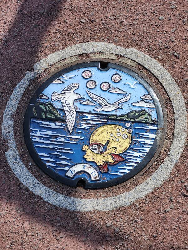 Multi-color painted manhole cover with Hakodate's squid mascot.