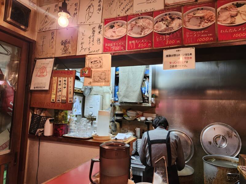 Cooking area and wall-mounted menu in a ramen restaurant in Daimon Yokocho.