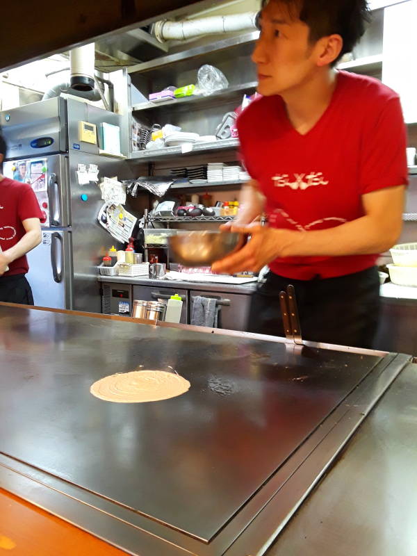 Okonomiyaki chef in Hiroshima, thin batter pancake.