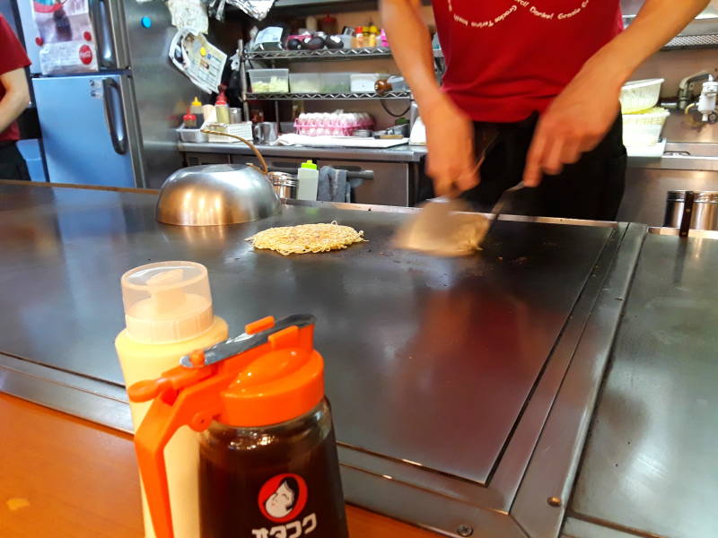 Okonomiyaki chef in Hiroshima flipping the stack.