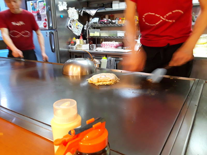 Okonomiyaki chef in Hiroshima flipping the stack.