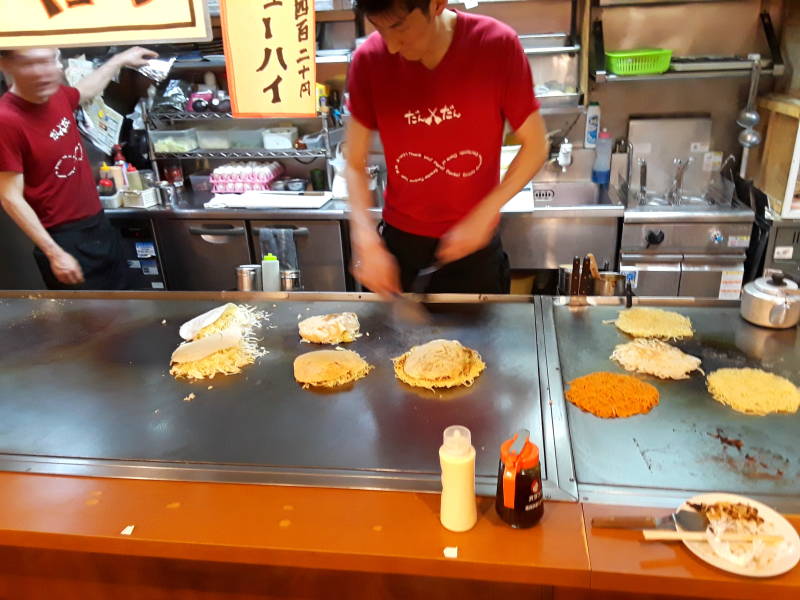 Okonomiyaki chef in Hiroshima, several meals underway.