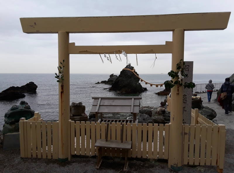 Looking through a torii to Meoto Iwa, the Wedded Rocks, joined by the holy rope shimenawa.