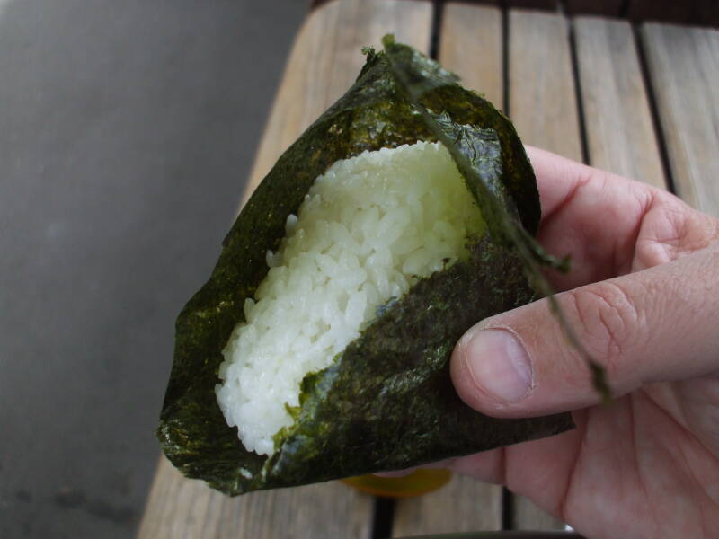 Unwrapping and eating o-nigiri, rice ball with fish, at Kita-Kamakura train station in Japan.