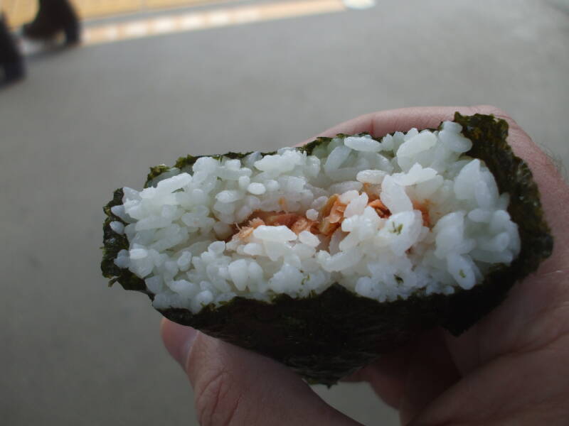 Unwrapping and eating o-nigiri, rice ball with fish, at Kita-Kamakura train station in Japan.