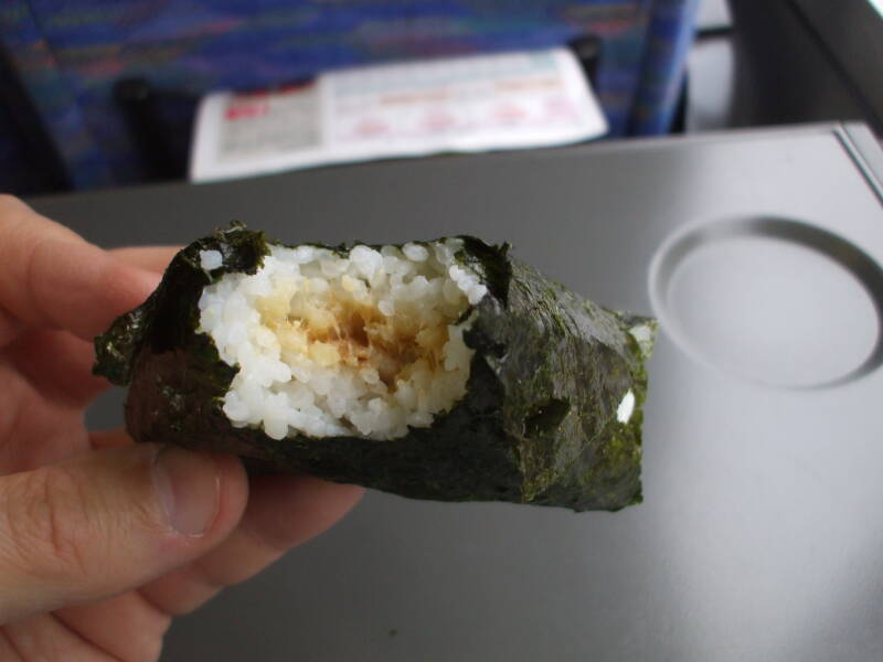 Unwrapping and eating o-nigiri, rice ball with fish, on board a train in Japan.