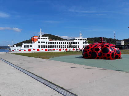 Inter-island ferry and Yayoi Kusuma 'Red Pumpkin' at Miyanoura port on Naoshima.