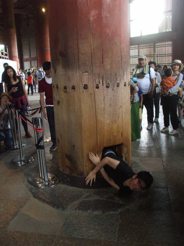 A young man crawls through the pillar at Tōdai-ji, the Buddhist temple in Nara.