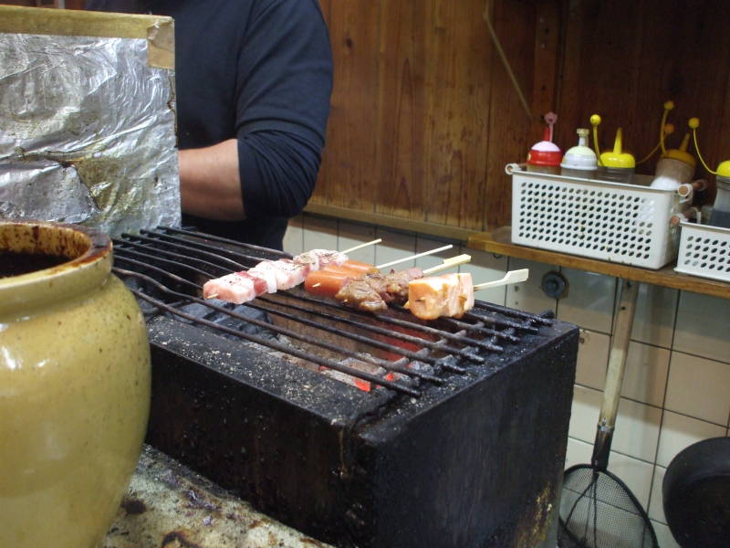 Yakitori on the grill in a small izakaya in Dōtonbori at night in Osaka.