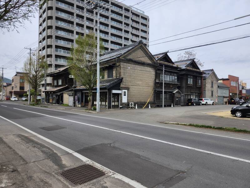 Otaru Taproom and Hostel beside some old wooden merchant buildings and in front of a new apartment building.