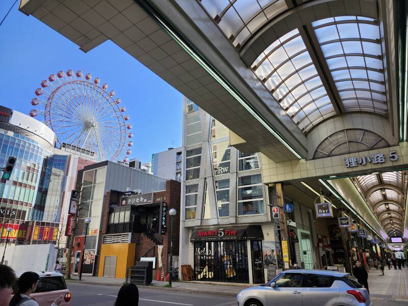 Tanukikoji Shopping Street crosses a street, large Ferris wheel to the left.